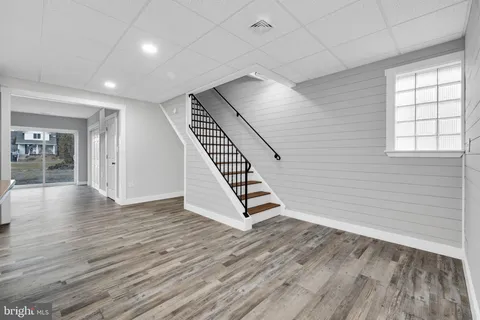 an empty room with wooden floor staircase and windows