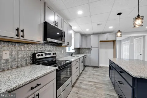 a kitchen with granite countertop a stove a sink and a microwave