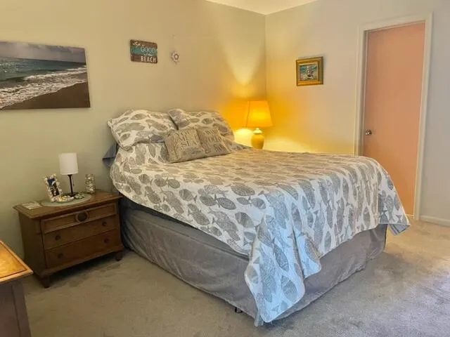 a bed sitting in a bedroom next to a wall painting and a lamp