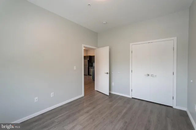 a view of an empty room with wooden floor and closet