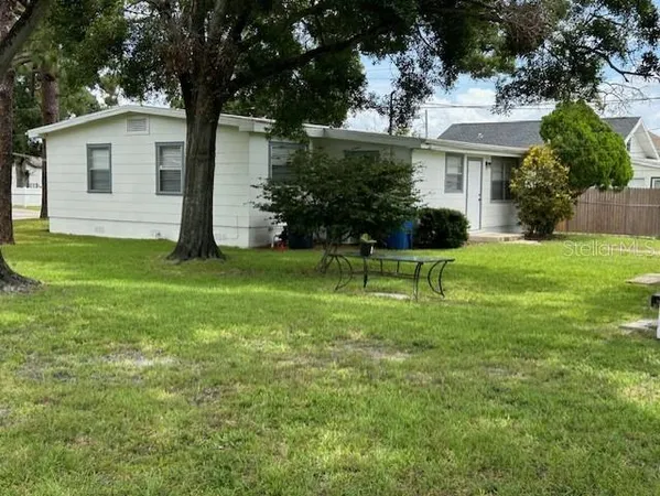 a view of a house with a yard and large trees