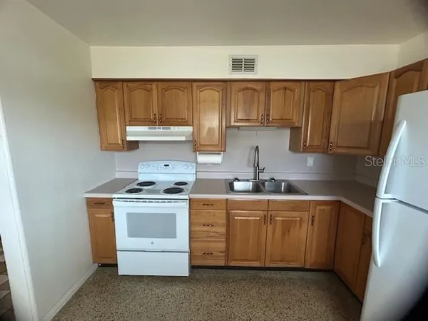 a kitchen with stainless steel appliances granite countertop a refrigerator sink a stove and white cabinets