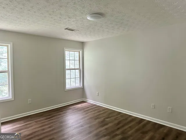 an empty room with wooden floor and window