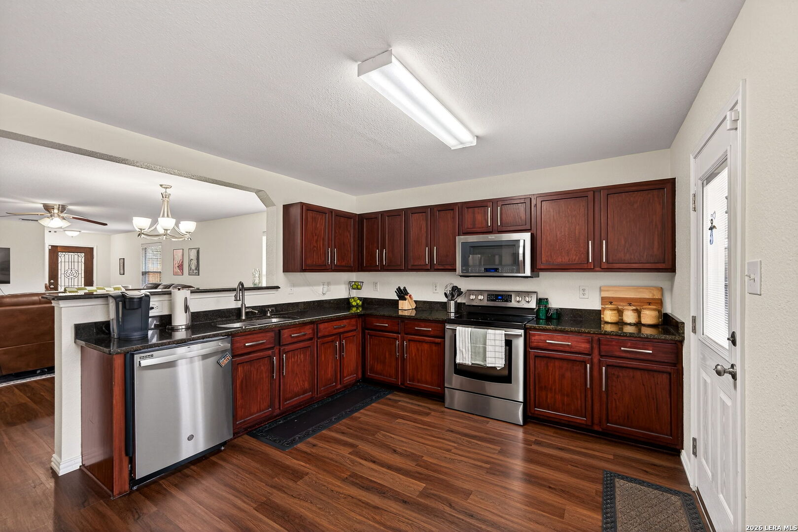 7942 Ruidoso Chase Selma, TX 78154 - Photo 12 of 26 a kitchen with stainless steel appliances granite countertop wooden cabinets a stove top oven a sink and dishwasher with wooden floor