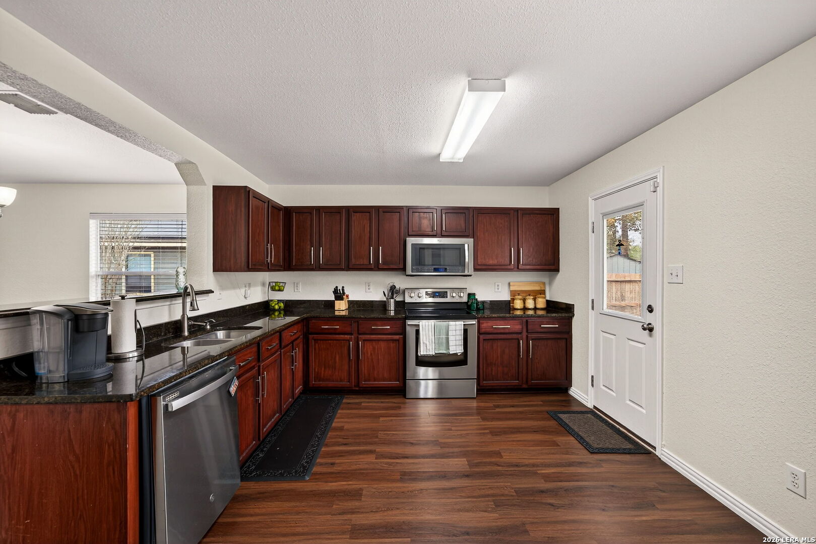 7942 Ruidoso Chase Selma, TX 78154 - Photo 13 of 26 a kitchen with stainless steel appliances granite countertop a stove top oven a sink dishwasher and a refrigerator with wooden floor