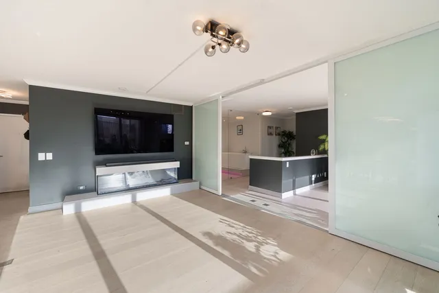 a living room with a flat screen tv and kitchen view