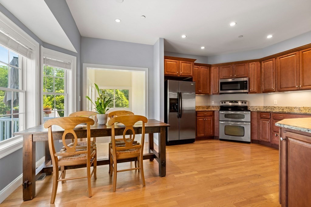 2 Hannah Dodge Road, Unit A Littleton, MA 01460 - Photo 6 of 28 a kitchen with stainless steel appliances granite countertop a stove a sink a microwave a dining table and chairs