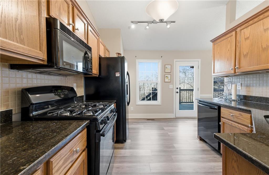 20 Miners Point Acworth, GA 30102 - Photo 7 of 21 a kitchen with stainless steel appliances granite countertop a stove top oven a sink dishwasher a dining table and chairs with wooden floor