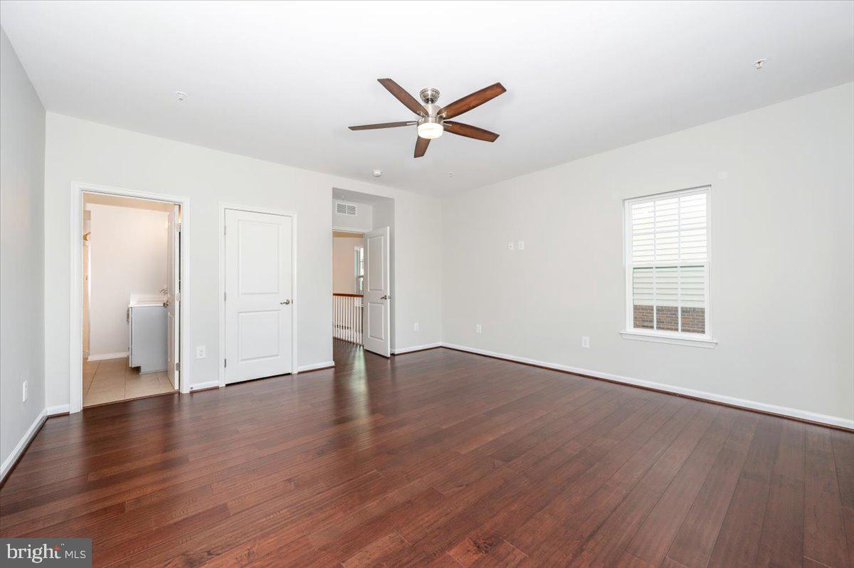 5059 Small Gains Way, Unit 5059 Frederick, MD 21703 - Photo 30 of 57 an empty room with wooden floor a ceiling fan and windows