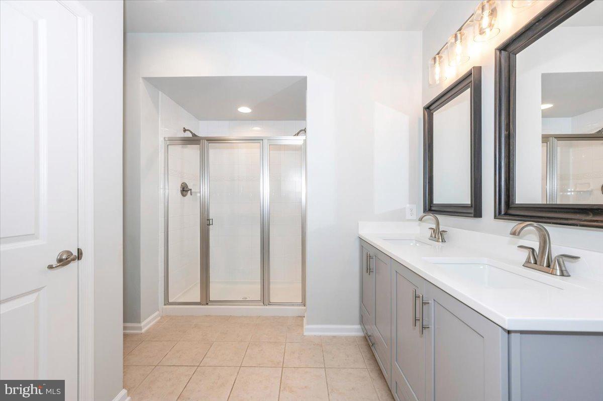 5059 Small Gains Way, Unit 5059 Frederick, MD 21703 - Photo 32 of 57 a bathroom with a double vanity sink a mirror and a shower
