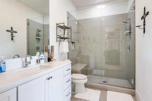 a bathroom with a shower sink vanity mirror and toilet