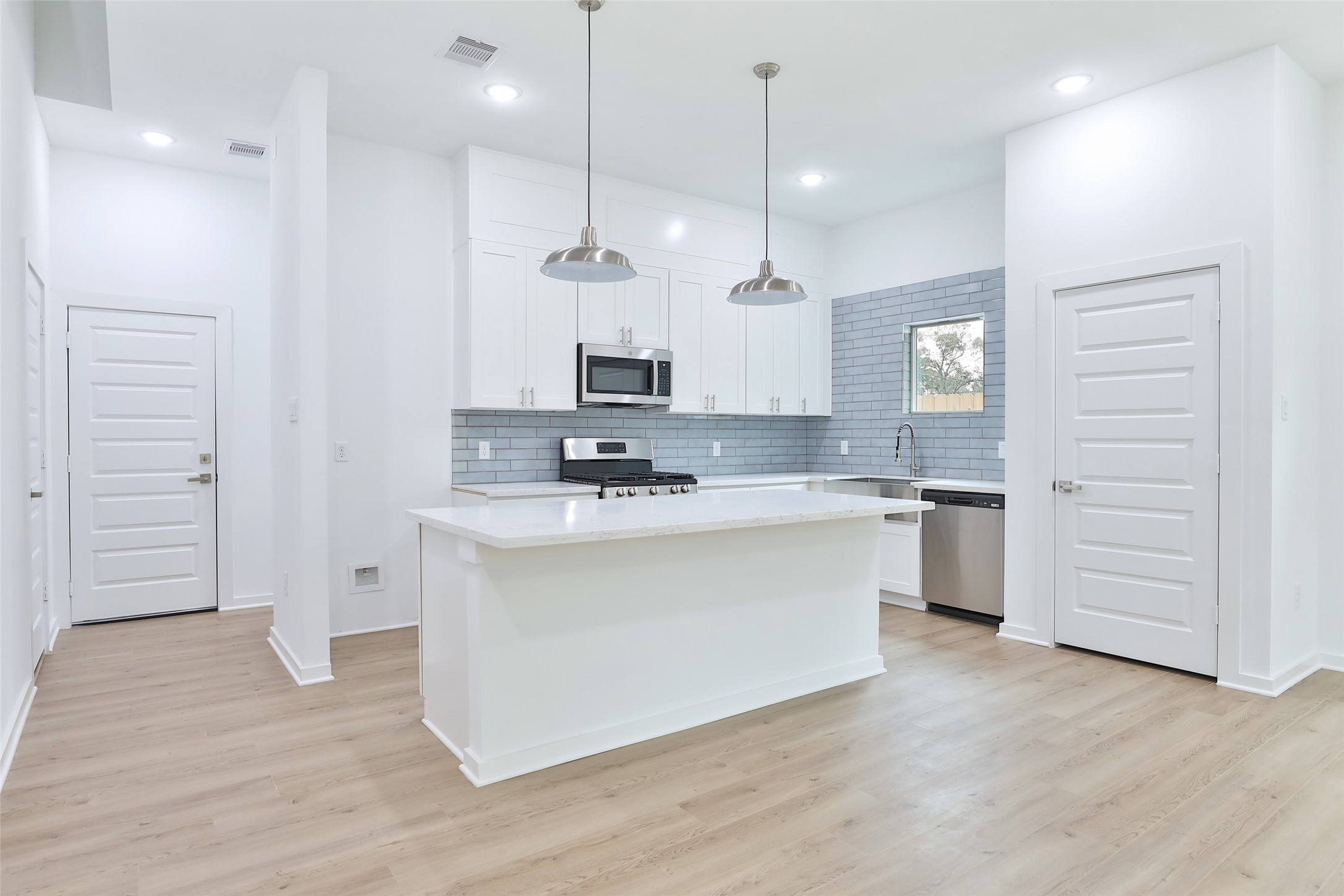 9349 Lavender Street Houston, TX 77016 - Photo 6 of 29 a kitchen with stainless steel appliances granite countertop a sink a stove a refrigerator and white cabinets with wooden floor