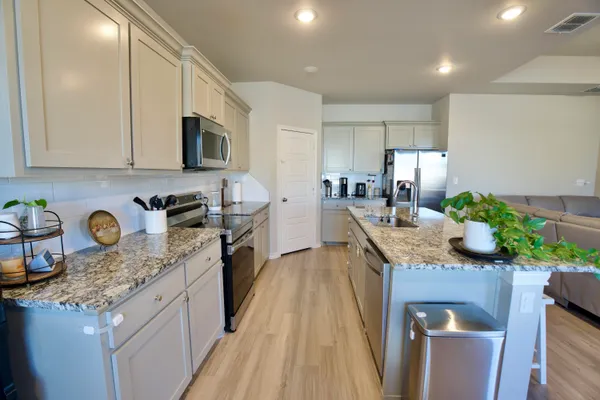 a kitchen with granite countertop kitchen island stainless steel appliances a sink a stove top oven a counter space and cabinets