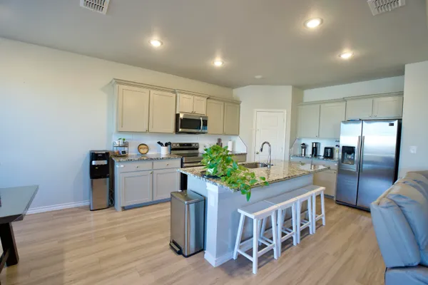 a kitchen with stainless steel appliances granite countertop a refrigerator a stove top oven a sink dishwasher and white cabinets with wooden floor
