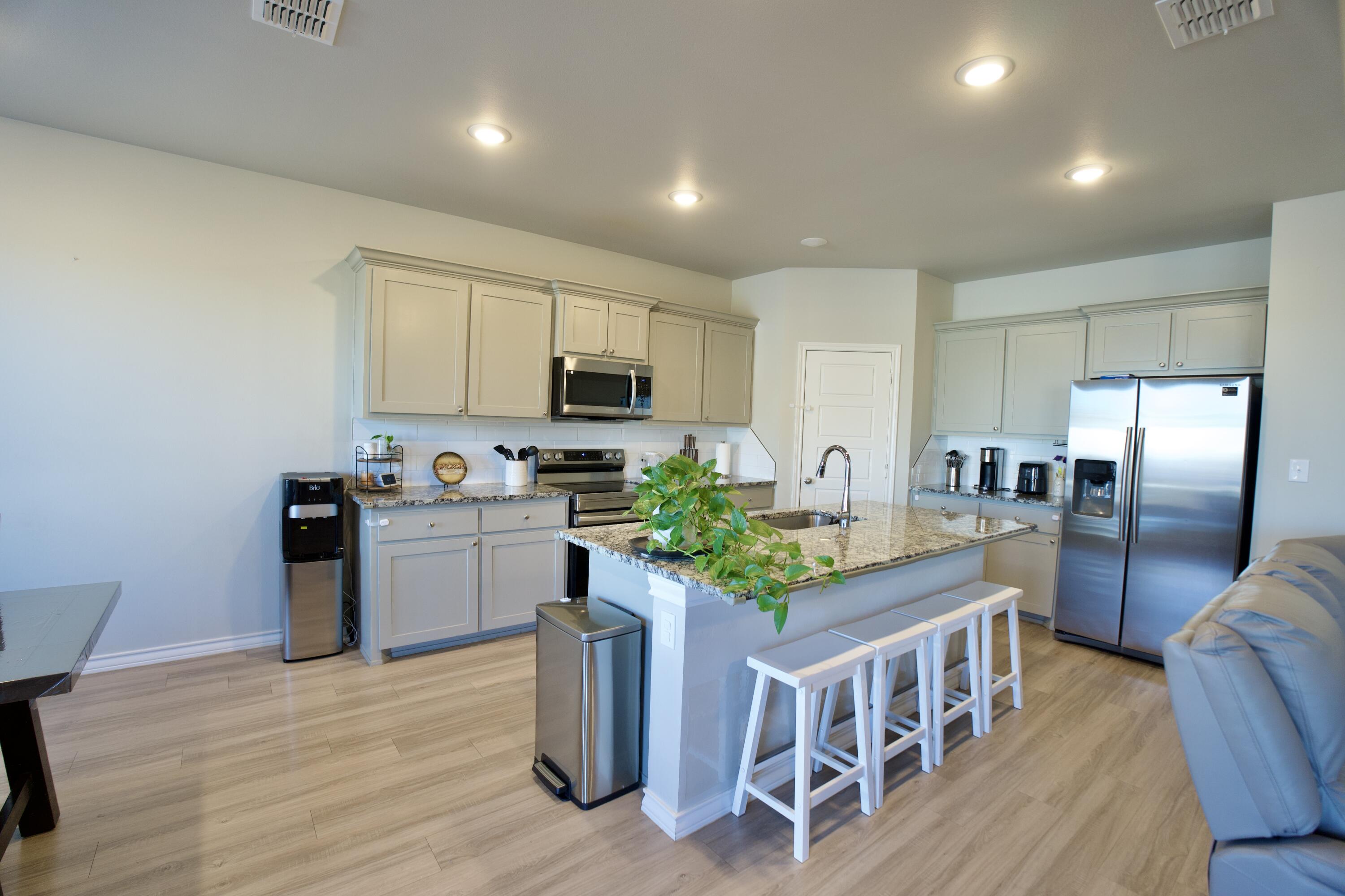5801 Winfield Avenue Lubbock, TX 79407 - Photo 6 of 20 a kitchen with stainless steel appliances granite countertop a refrigerator a stove top oven a sink dishwasher and white cabinets with wooden floor