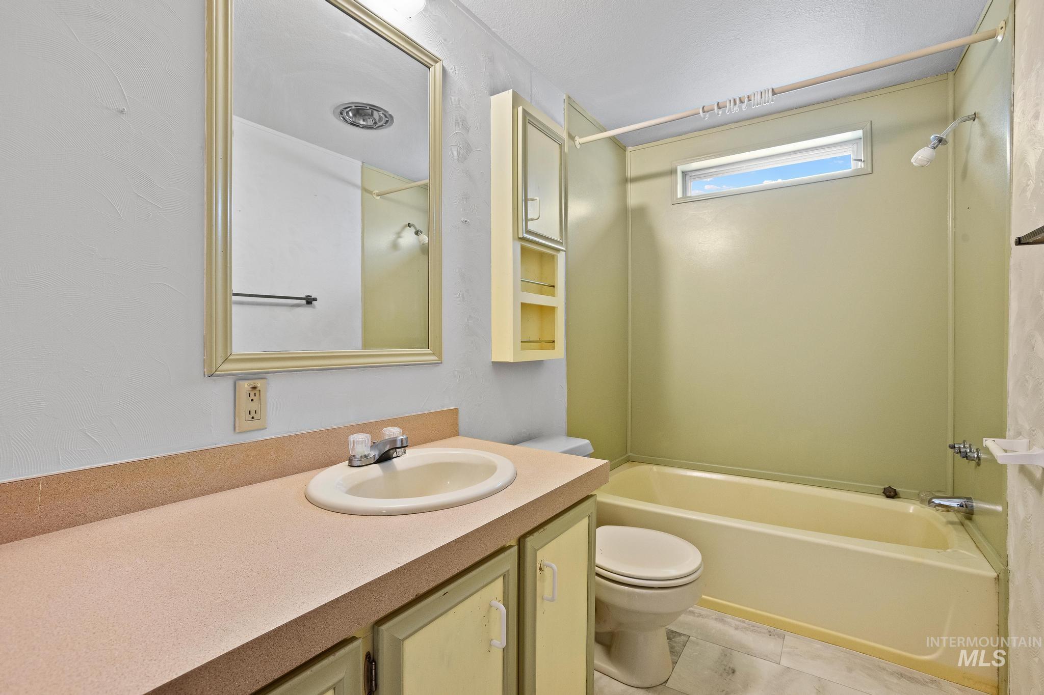 3680 South Mill Road Emmett, ID 83617 - Photo 25 of 38 Bathroom featuring a vanity with an integrated sink, a framed mirror, an overhead light fixture, a built-in storage cabinet, and a bathtub with an overhead shower