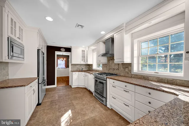 a large kitchen with stainless steel appliances granite countertop a stove a sink and a granite counter tops