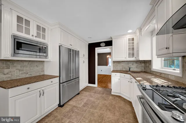 a kitchen with stainless steel appliances granite countertop a refrigerator and a stove top oven