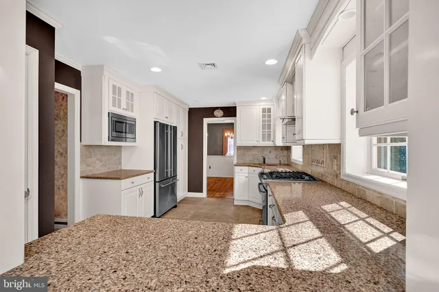 a kitchen with stainless steel appliances granite countertop a stove top oven a sink and a refrigerator