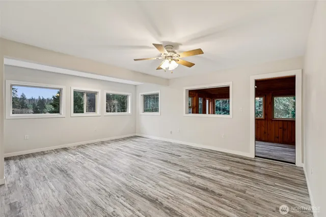 a view of an empty room with window and wooden floor