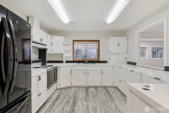 a kitchen with white cabinets stainless steel appliances a sink and a window