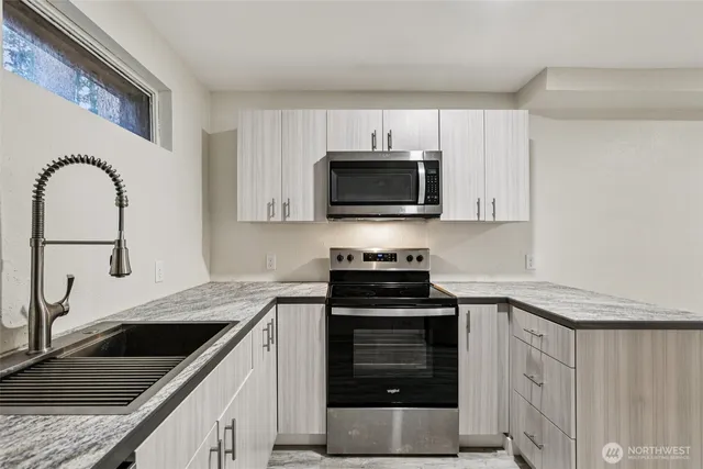 a kitchen with granite countertop a sink and a stove top oven with wooden floor