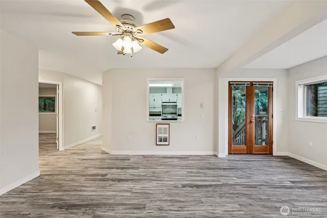 a view of an empty room with window and wooden floor