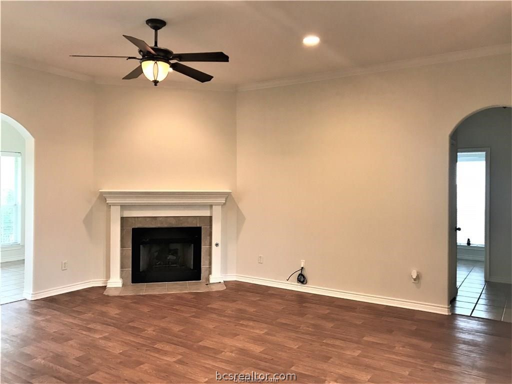 3754 Essen Loop College Station, TX 77845 - Photo 2 of 25 an empty room with wooden floor a ceiling fan and a fireplace