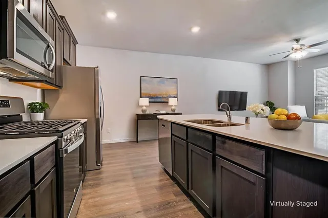 a kitchen with stainless steel appliances a sink dishwasher stove refrigerator and wooden floor