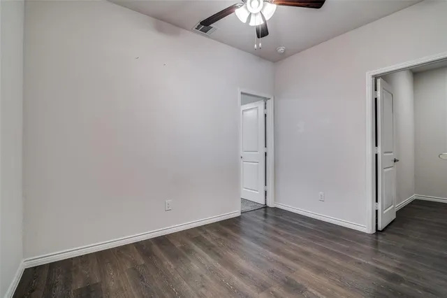 an empty room with wooden floor chandelier fan and closet area