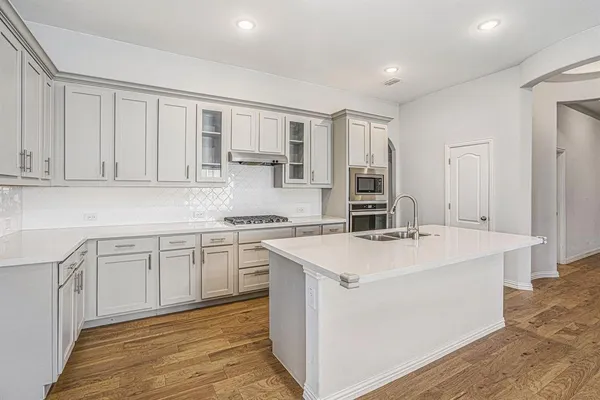 a kitchen with white cabinets appliances and sink