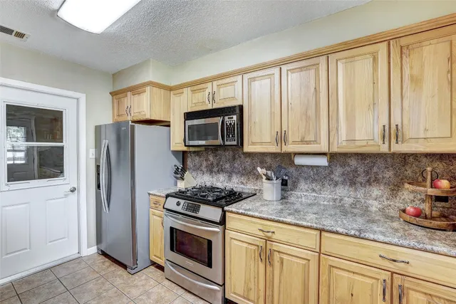 a kitchen with stainless steel appliances granite countertop white cabinets a refrigerator and a stove top oven