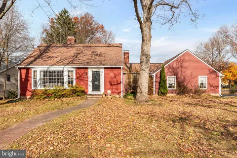 a front view of a house with a dirt yard and a large tree