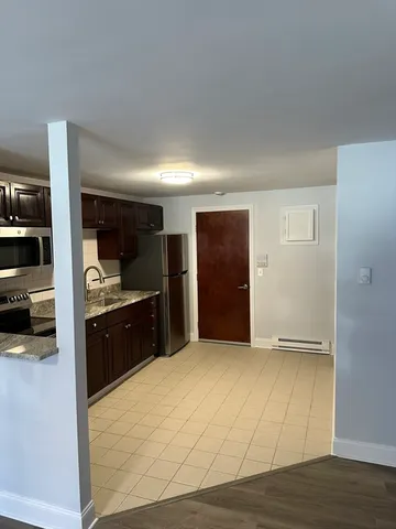 a room with a dresser and a refrigerator