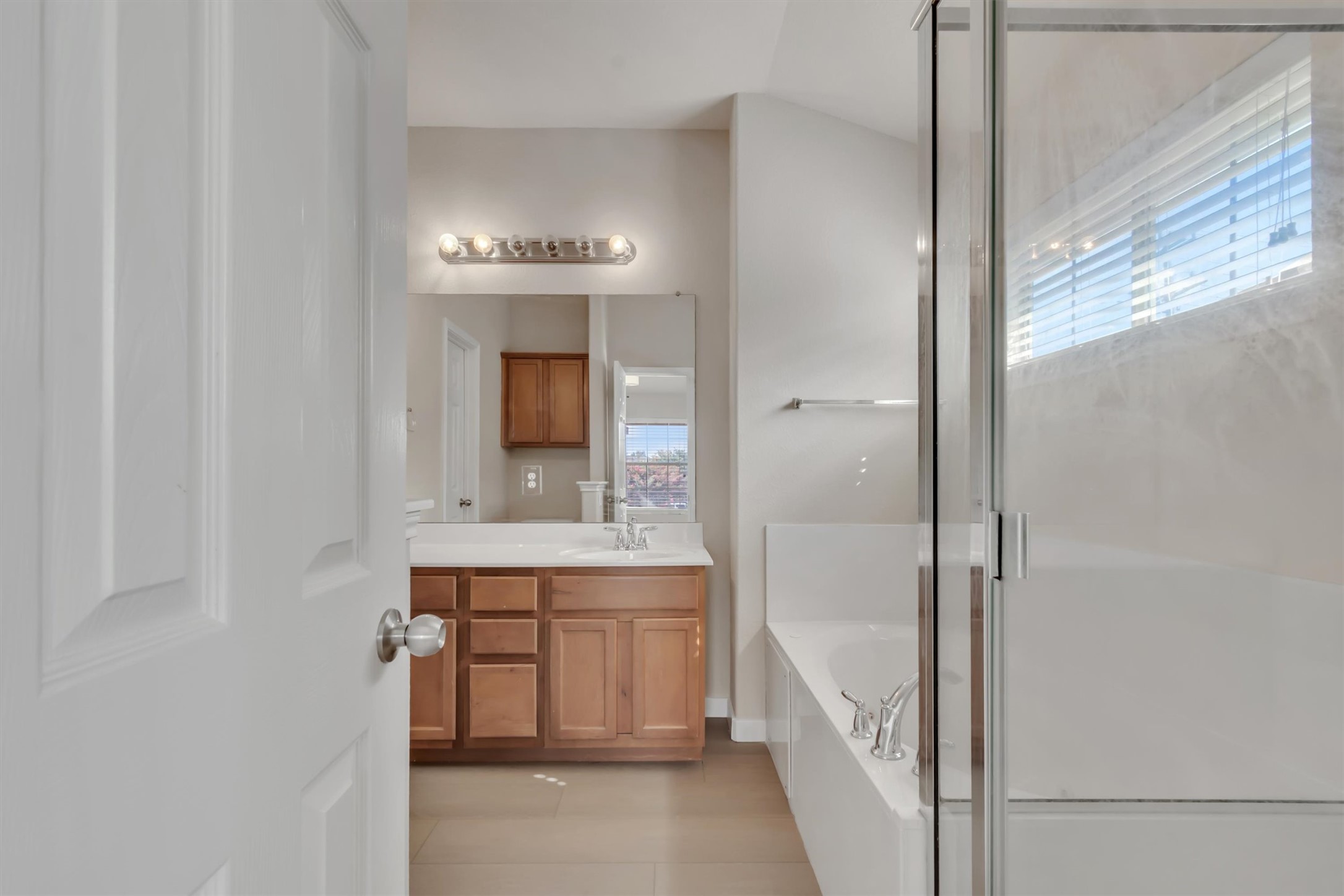 14815 Avery Ranch Boulevard, Unit 2A Austin, TX 78717 - Photo 16 of 27 Clean lines define this bathroom, featuring a single vanity, soaking tub, and glass-enclosed shower.