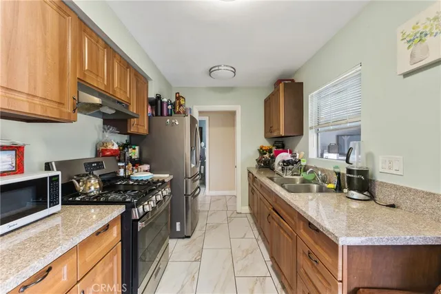 a kitchen with granite countertop a sink stove and refrigerator
