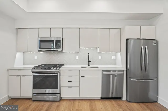 a kitchen with cabinets stainless steel appliances and wooden floor