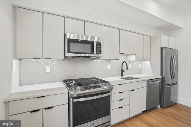 a kitchen with stainless steel appliances white cabinets and a stove top oven