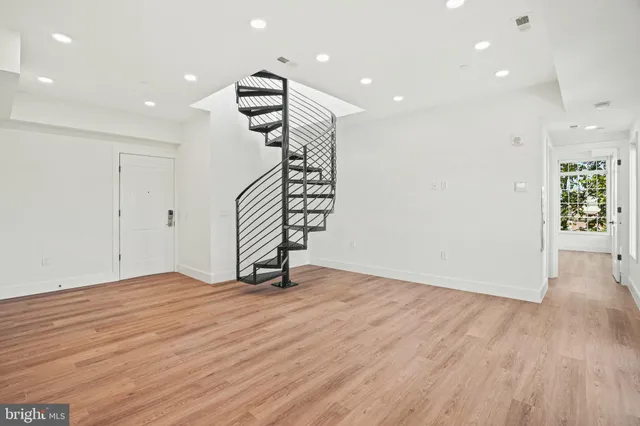 a view of an empty room with wooden floor and stairs