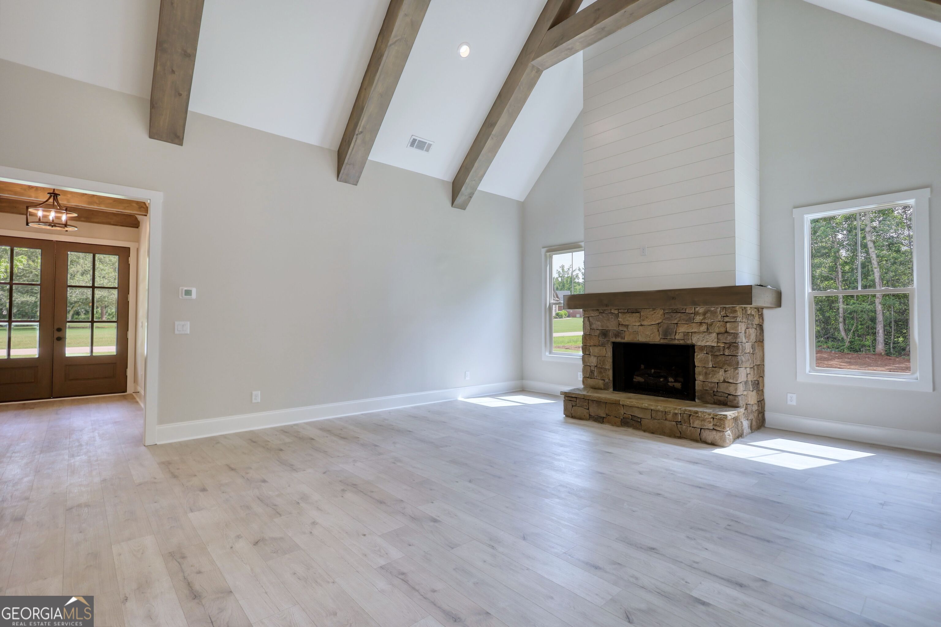 1031 Graham Drive Madison, GA 30650 - Photo 40 of 78 an empty room with wooden floor fireplace and windows