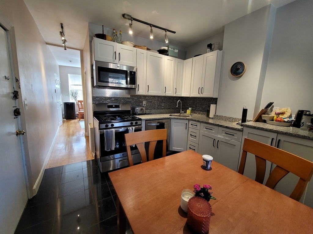 11 Phillips Street, Unit 8 Boston, MA 02114 - Photo 1 of 14 a kitchen with granite countertop a sink stainless steel appliances and cabinets