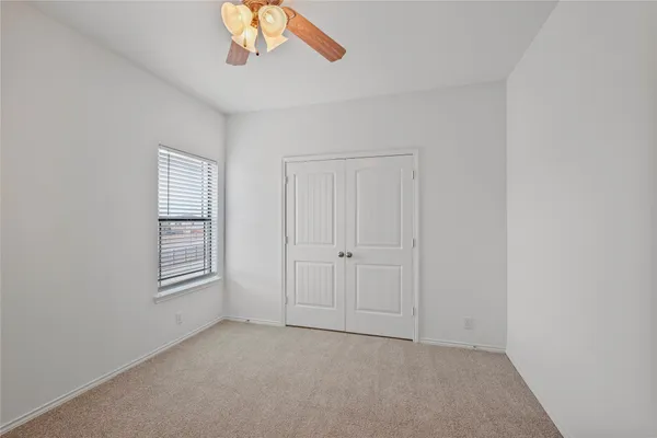 an empty room with windows and chandelier fan