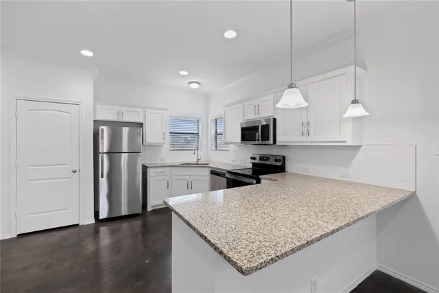 a kitchen with stainless steel appliances granite countertop a refrigerator a stove a microwave oven a sink with a dining table and chairs