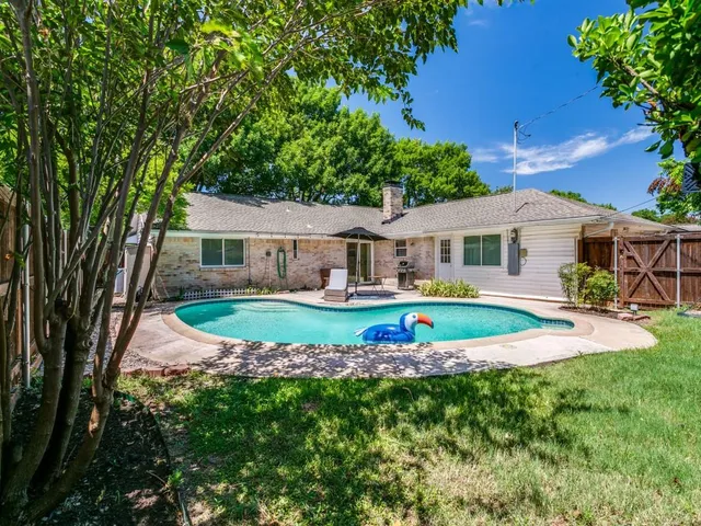 a view of house with swimming pool and yard