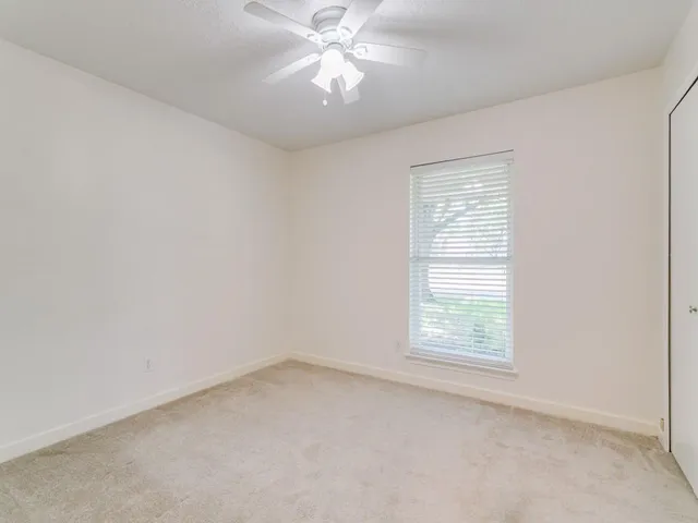 an empty room with a window and a fan