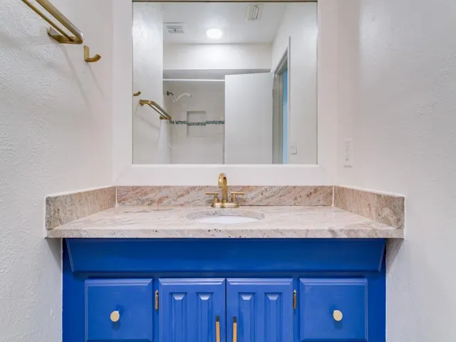 a bathroom with a granite countertop sink and a mirror