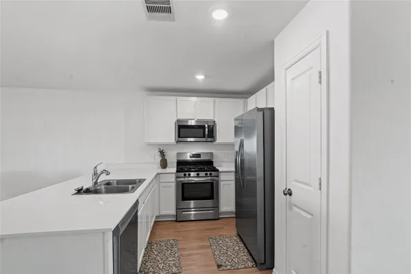 a kitchen with stainless steel appliances a refrigerator a sink a stove and cabinets