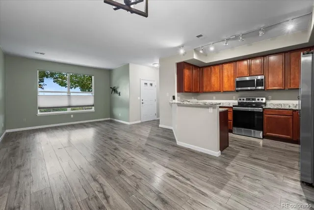 a kitchen with stainless steel appliances granite countertop wooden cabinets a stove top oven a sink and dishwasher with wooden floor