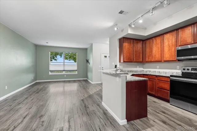 a kitchen with stainless steel appliances granite countertop wooden cabinets a stove top oven a sink and dishwasher