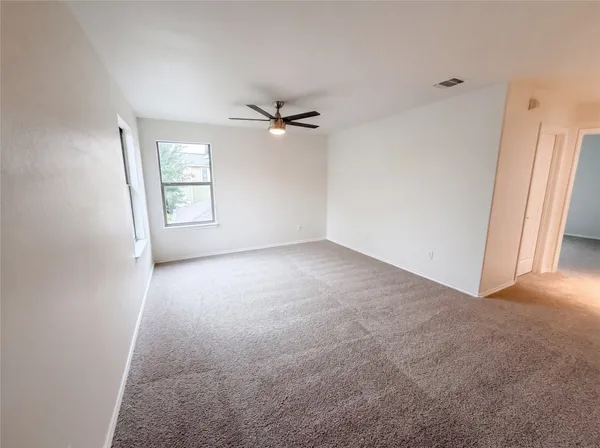an empty room with windows and fan